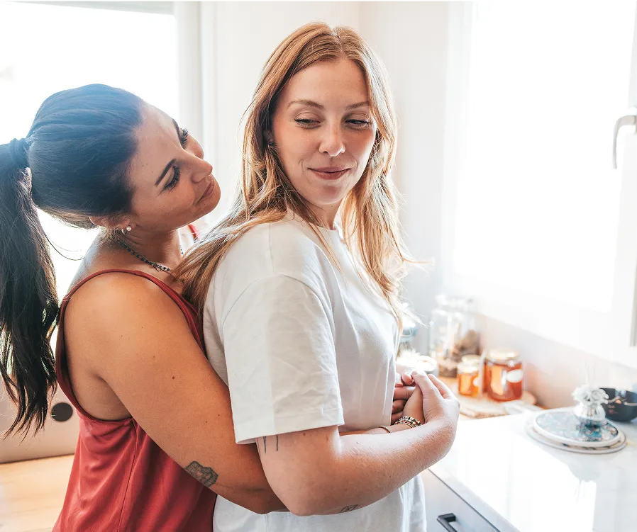 Two women in an embrace standing in a kitchen