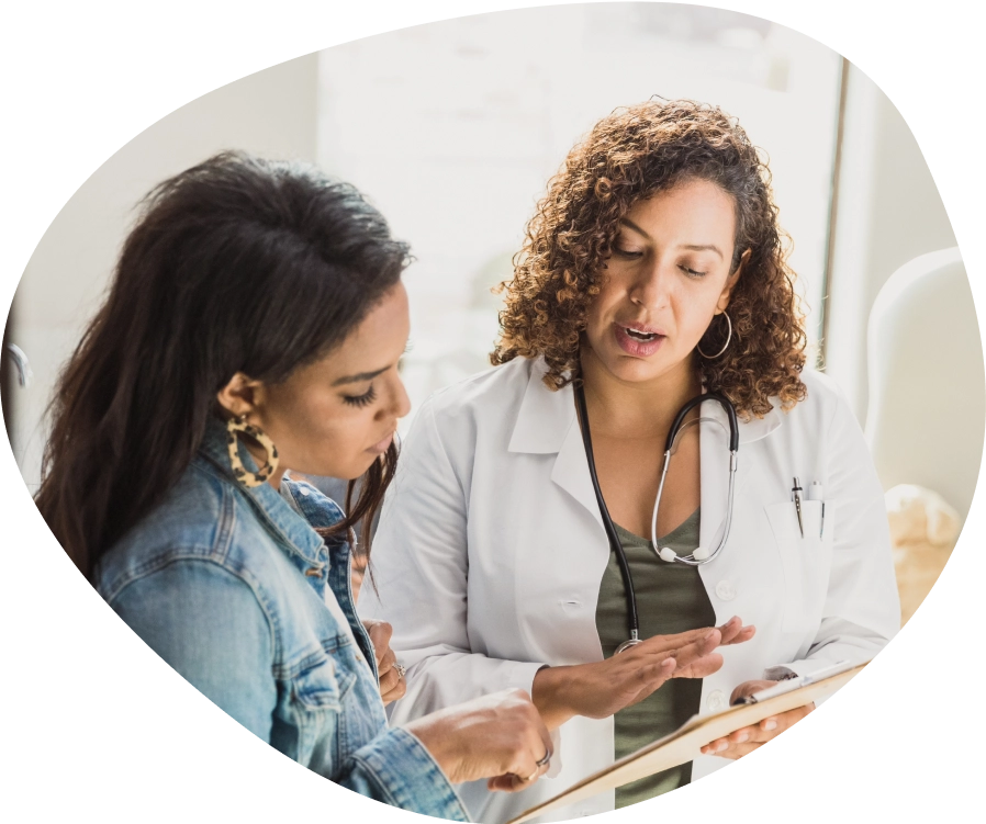 A woman with a healthcare professional looking at something on a clipboard